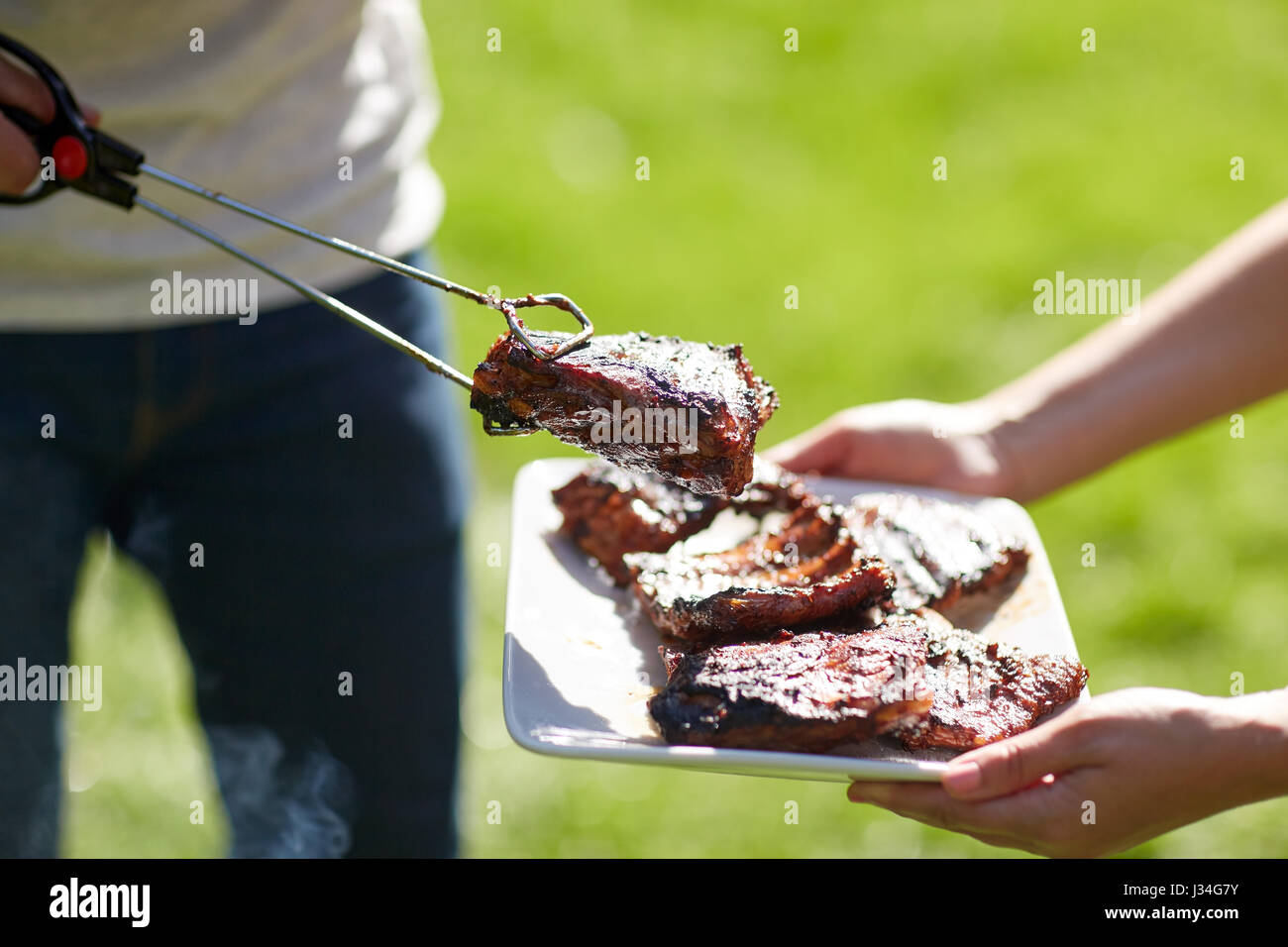 L'uomo la cottura della carne in estate barbecue party Foto Stock