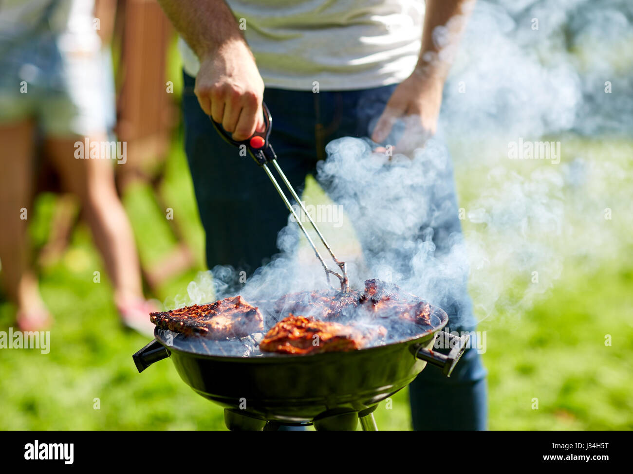 L'uomo la cottura della carne sul barbecue grill al Summer Party Foto Stock
