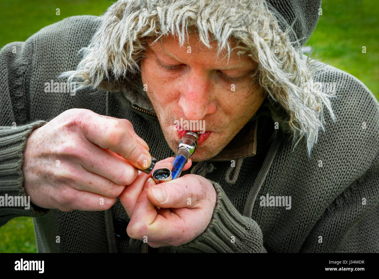 Farmaco illuminazione utente il suo tubo di cannabis, Glasgow, Scotland, Regno Unito Foto Stock