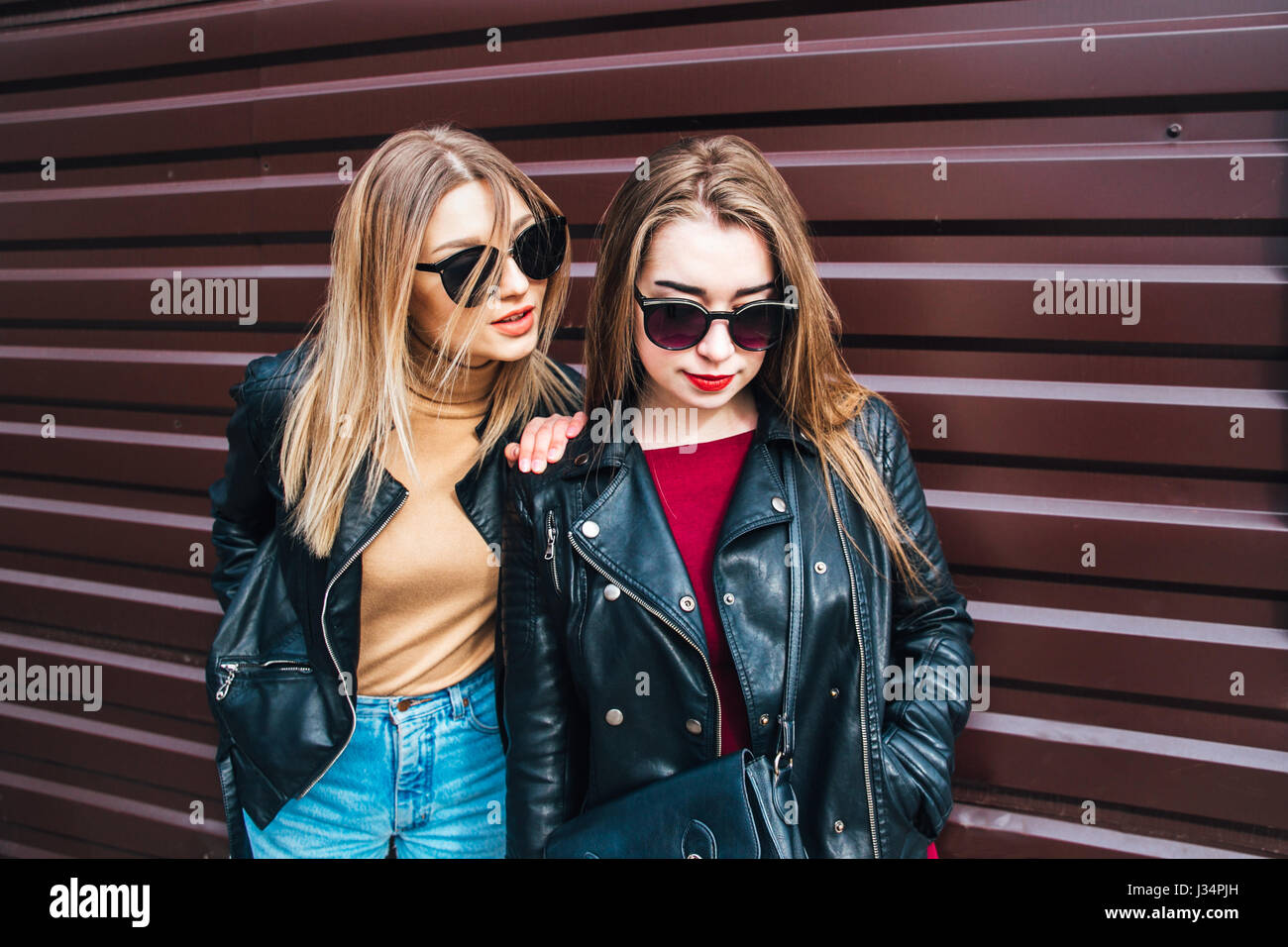 Conversazione tra due donne nella città.Outdoor Lifestyle ritratto di due migliori amici hipster ragazze indossano Elegante giacca di pelle e occhiali da sole, going crazy e avente un grande tempo insieme Foto Stock