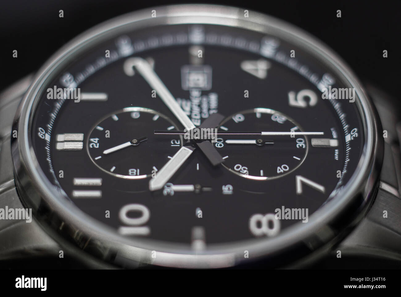 Immagine ravvicinata di un acciaio inossidabile orologio analogico, con grande sfera nera in uno sfondo nero, dal lato. Foto Stock