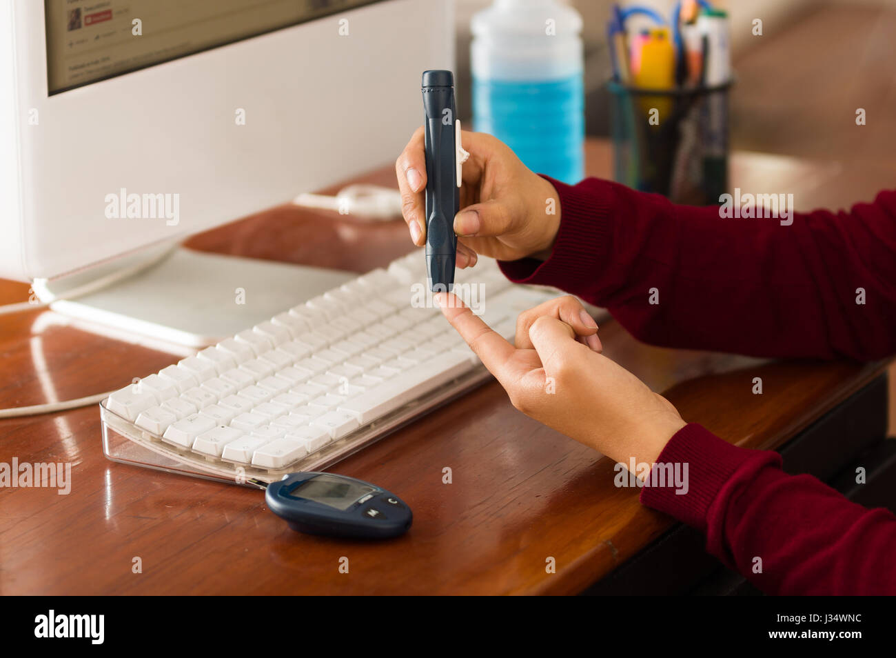 Donna controllo livello di zucchero nel sangue dal glucometro e striscia di prova mentre lei sta lavorando Foto Stock