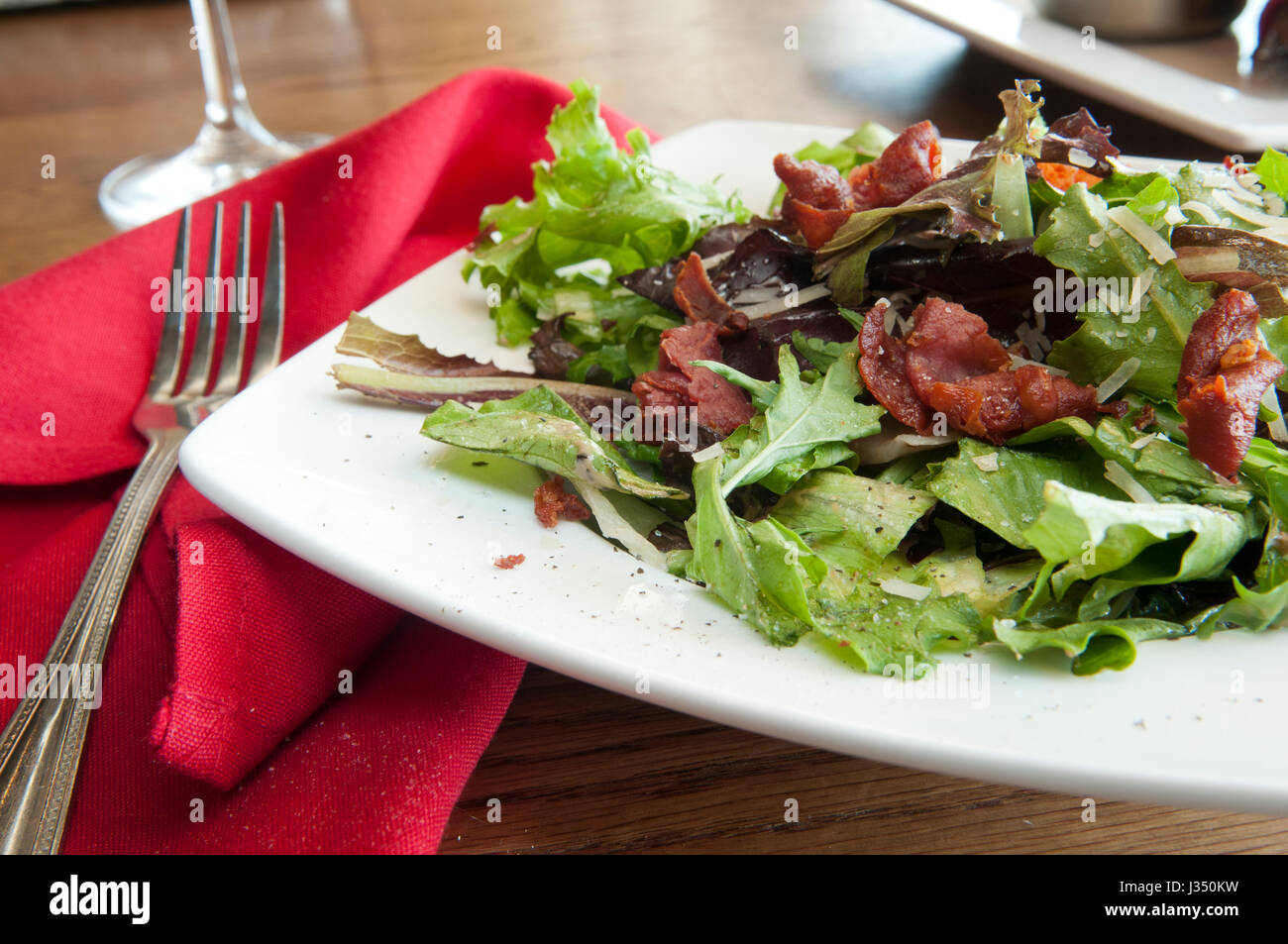 Close up di verdure miste per insalata con pancetta croccante, parmigiano grattugiato e pepe nero pestato, in un ristorante di impostazione Foto Stock