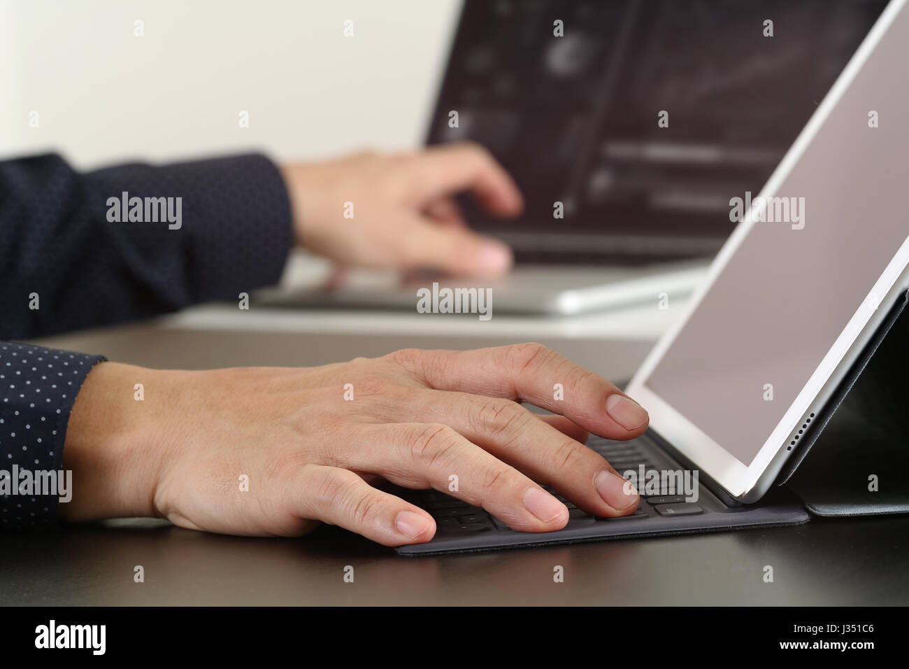 Stretta di mano imprenditore lavora con il computer portatile e digitale tastiera docking tablet pc in ufficio moderno Foto Stock