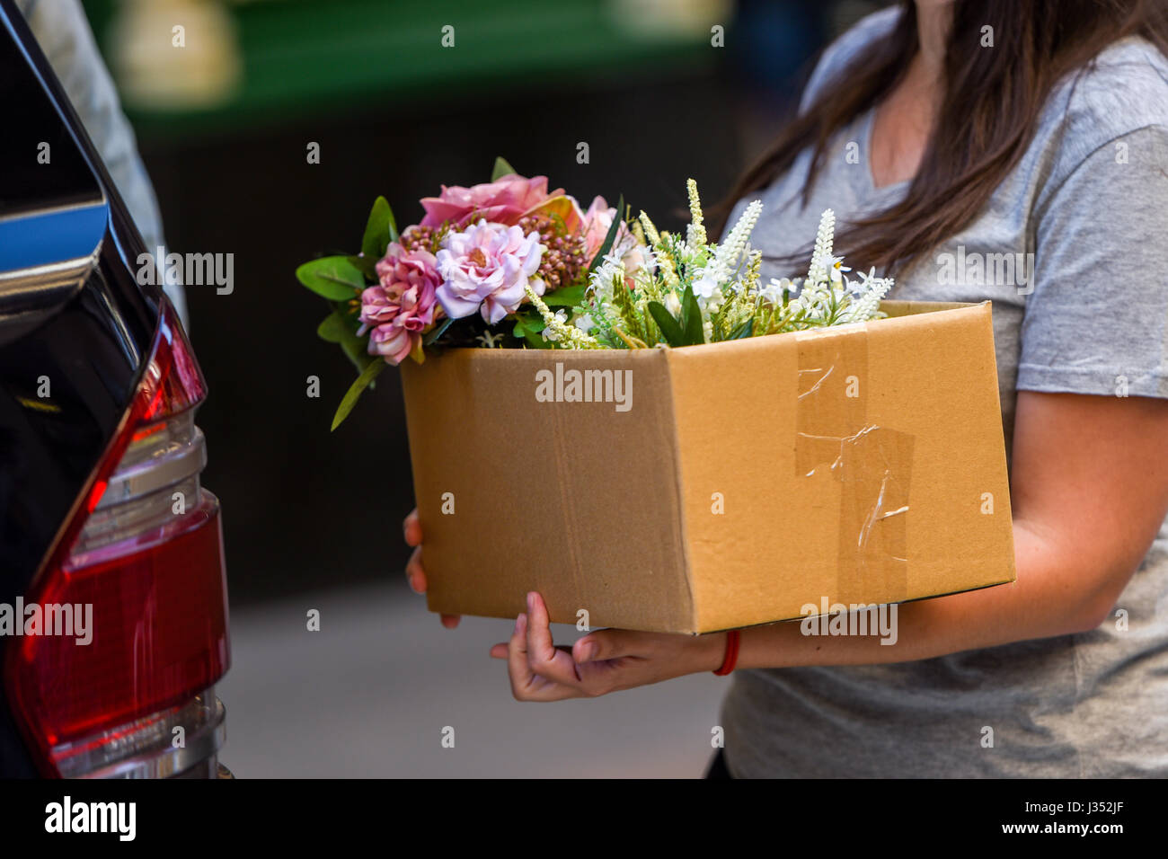 Persone che trasportano le caselle con i fiori Foto Stock