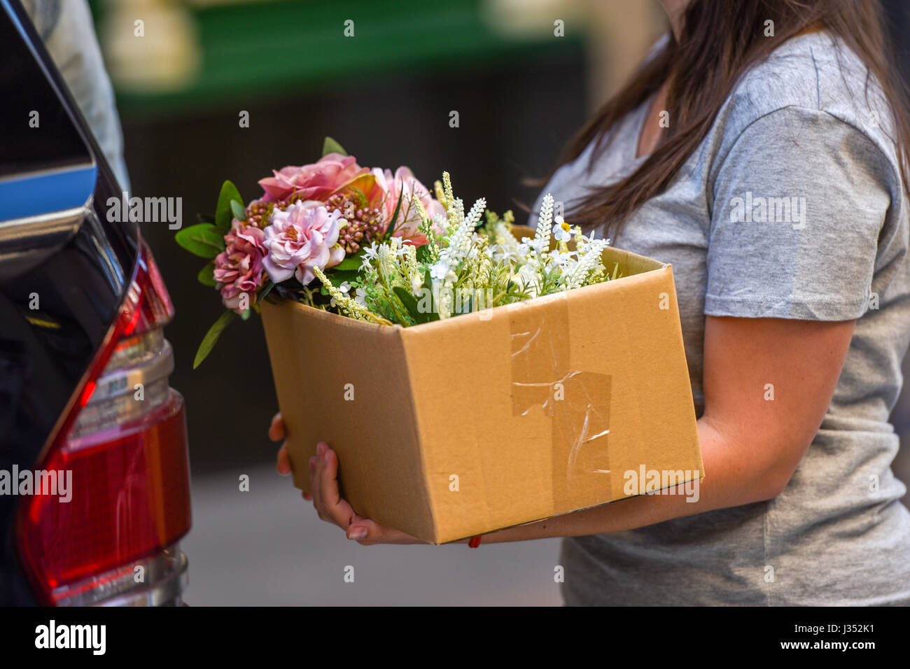 Persone che trasportano le caselle con i fiori Foto Stock
