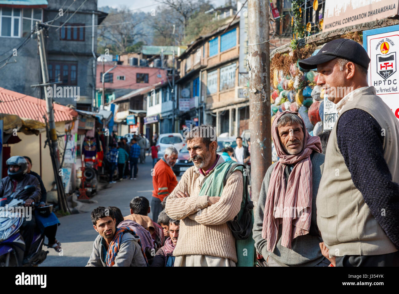 Stile di vita indiano: locale uomini stavano in piedi attorno aspettando pazientemente in una strada affollata in McLeodGanj, Dharamshala, Himachal Pradesh, India del nord Foto Stock