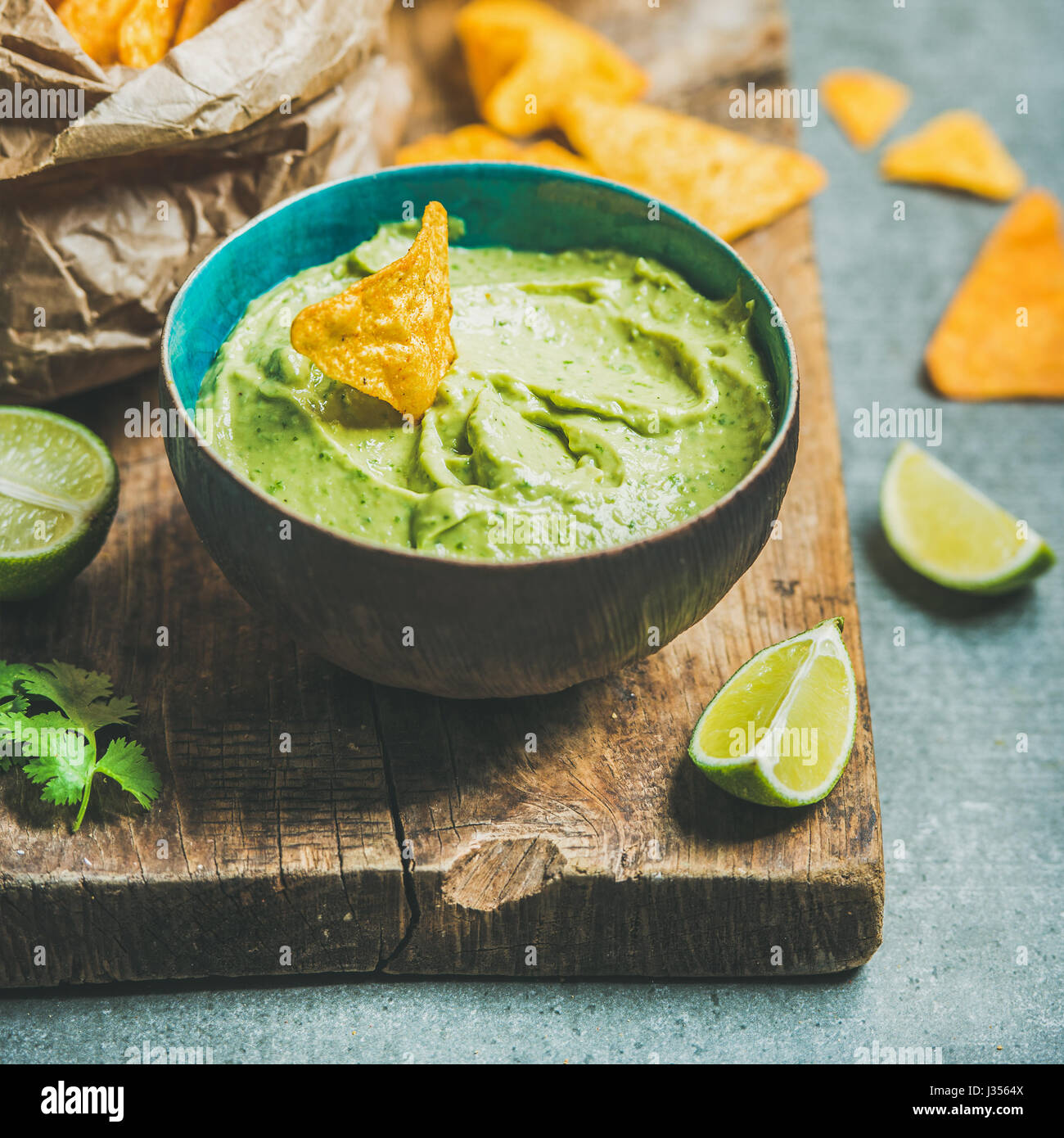 Guacamole fresco salsa in vaso blu e patatine, quadrato ritaglia Foto Stock