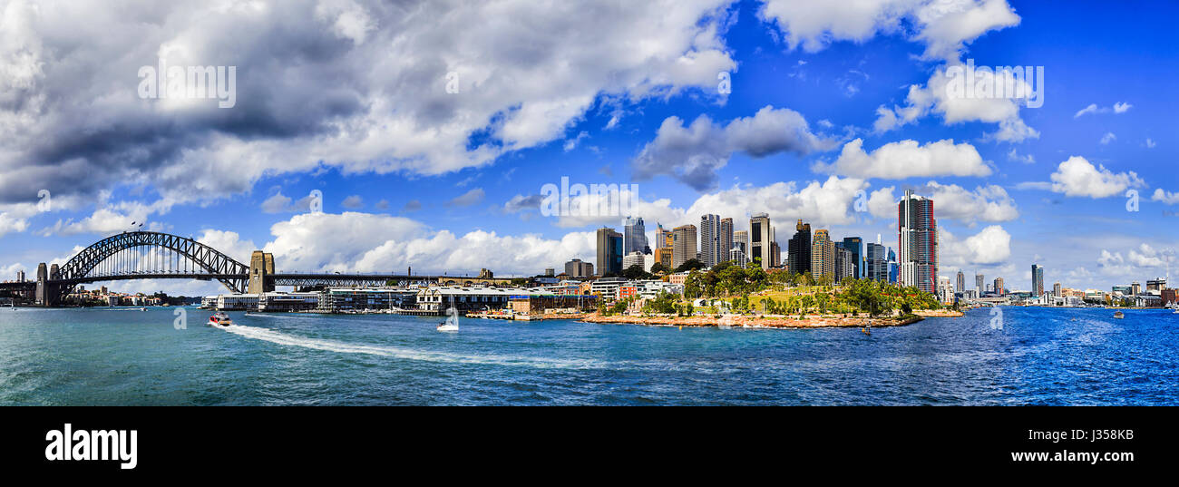 Panorama della città di Sydney waterfront da nord e Sydney Harbour Bridge attraverso le rocce, molo di Barangaroo a Darling Harbour e Pyrmont in una giornata di sole. Foto Stock