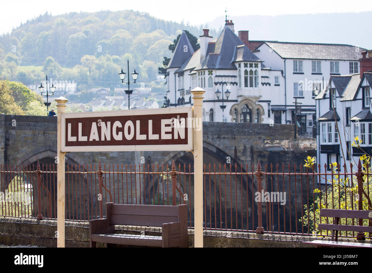 Llangollen stazione ferroviaria firmare con la città in background e il ponte che attraversa il fiume Dee in Llangollen, Denbighshire Foto Stock