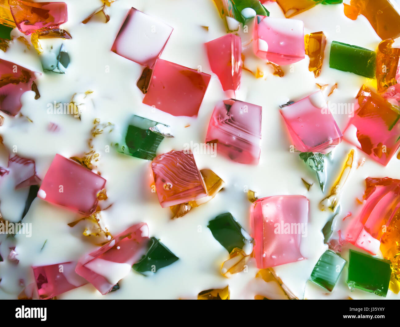 Delizioso e colorato dolce con pasto fatto di vetro trasparente colorato fette di gelatina viene riempito a metà crema bianca budino di latte. Il piatto perfetto Foto Stock