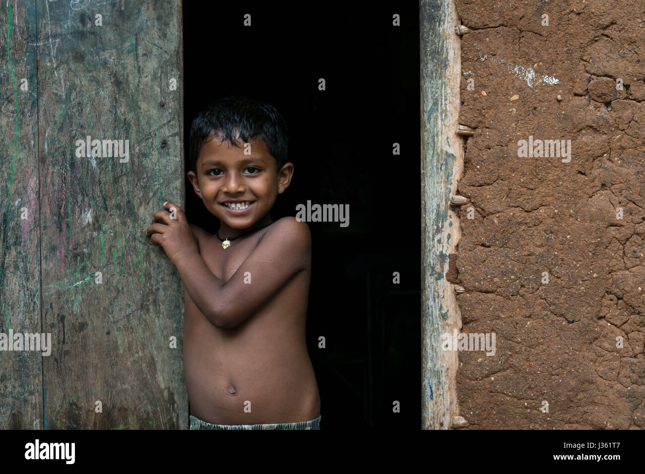 Un bambino sorrisi a un villaggio in HAMBANTOTA anche se queste famiglie sono colpite con la povertà. Foto Stock