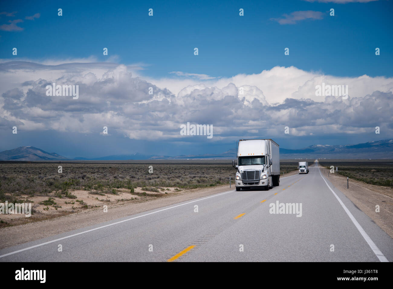 White semi camion big rig viaggiando su una rotta commerciale per la corretta consegna delle merci attraverso le praterie sull'altopiano di Nevada Foto Stock