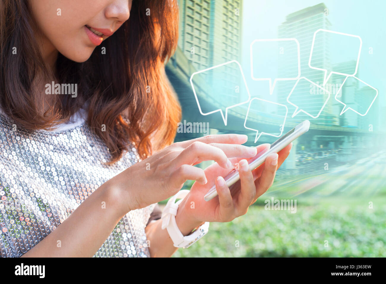 Close up più giovane donna toccando sullo smart phone schermo e citazioni bolla fluttuante città contro la costruzione di sfondo Foto Stock