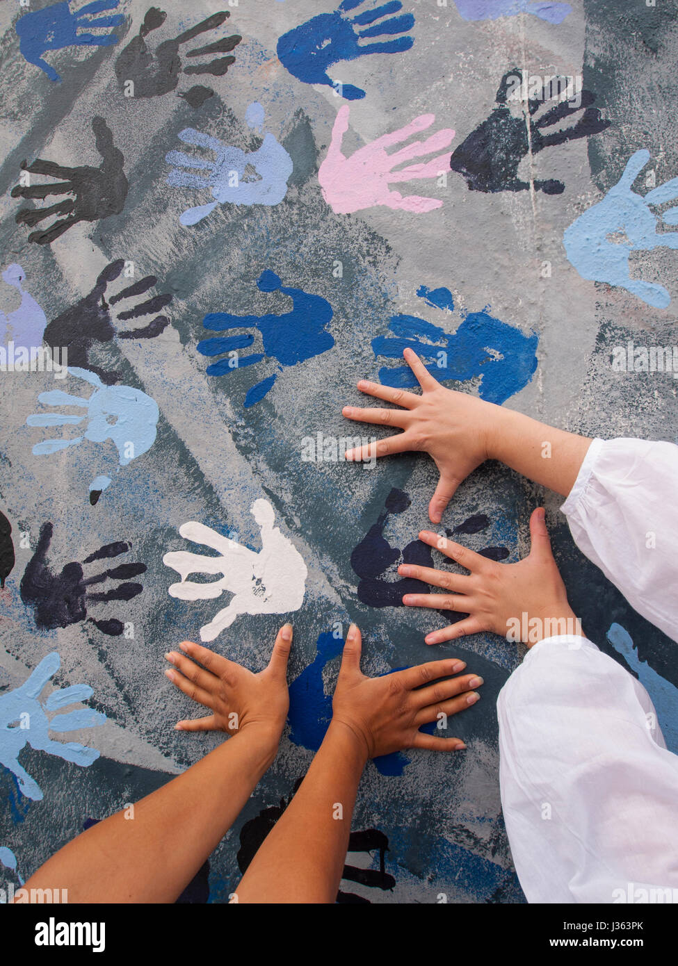 I turisti mettere le mani sul murale dipinto a muro di Berlino a East Side Gallery di Berlino, Germania Foto Stock