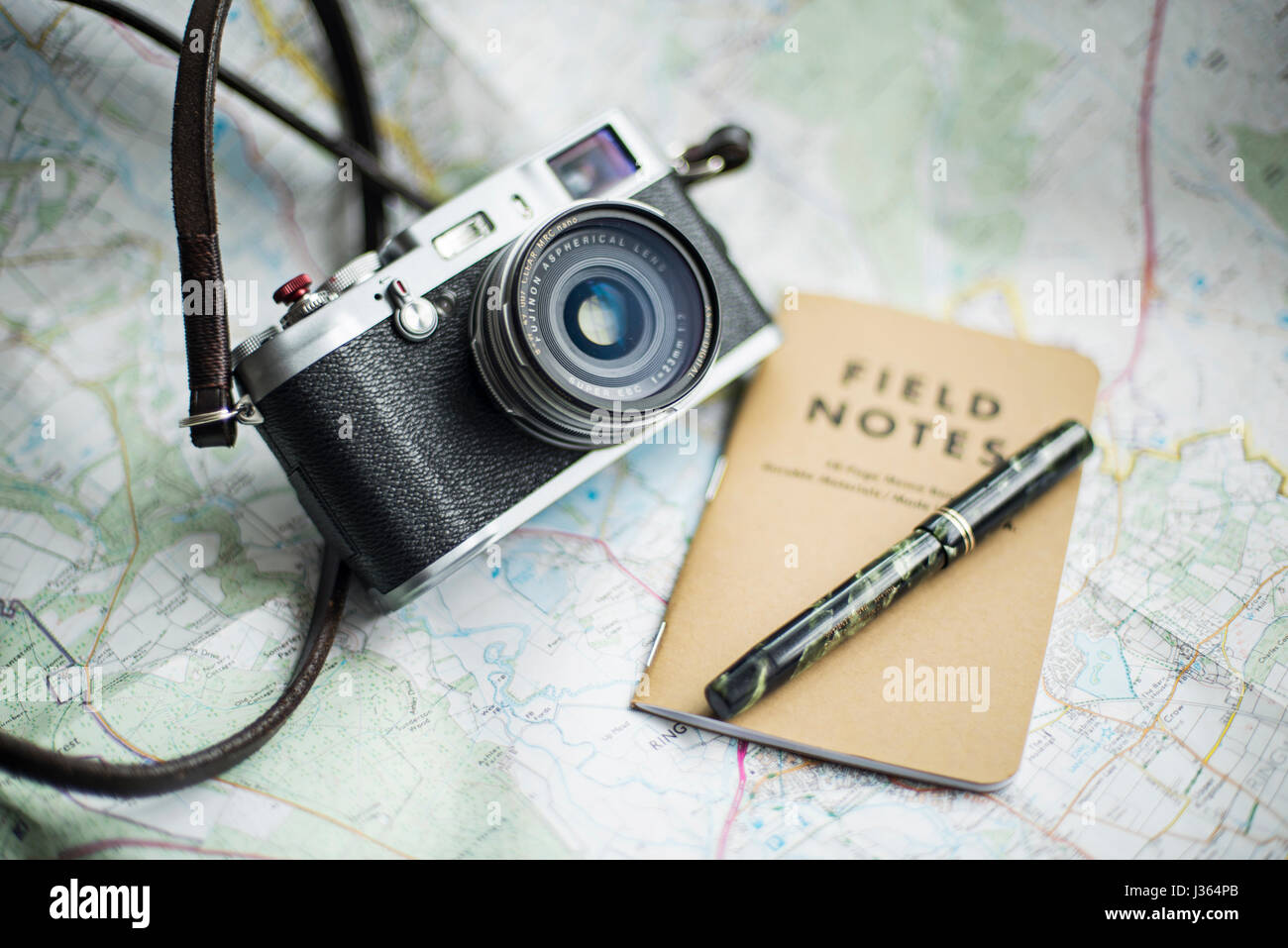 Fuji x100 fotocamera sulla mappa con il campo Note e notebook green Mabie Todd vintage fountain pen. Foto Stock