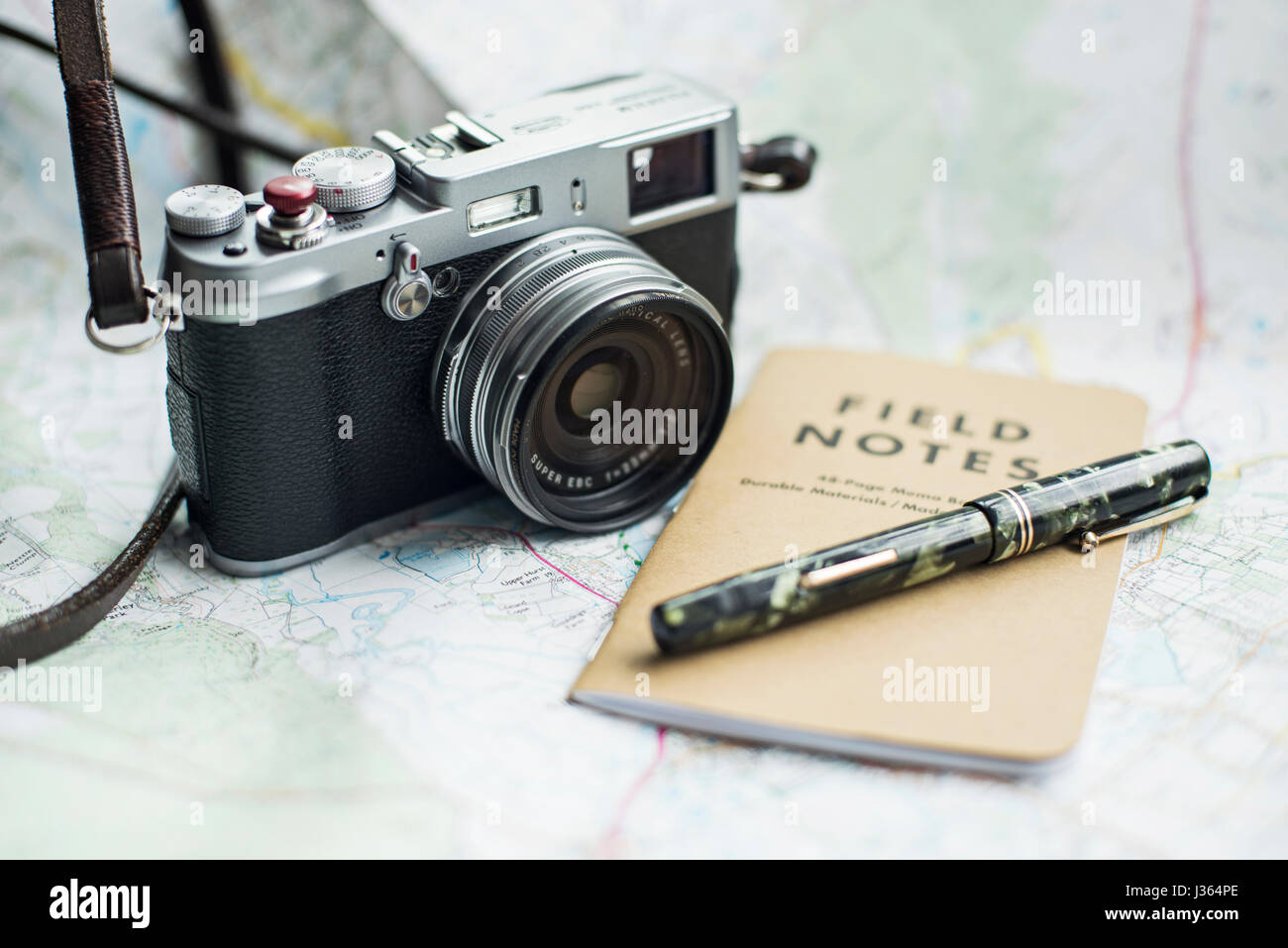 Fuji x100 fotocamera sulla mappa con il campo Note e notebook green Mabie Todd vintage fountain pen. Foto Stock