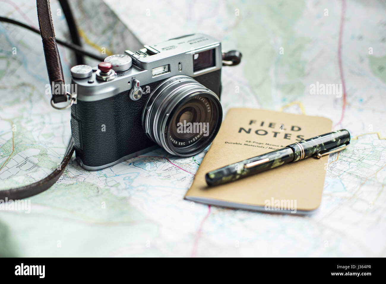 Fuji x100 fotocamera sulla mappa con il campo Note e notebook green Mabie Todd vintage fountain pen. Foto Stock