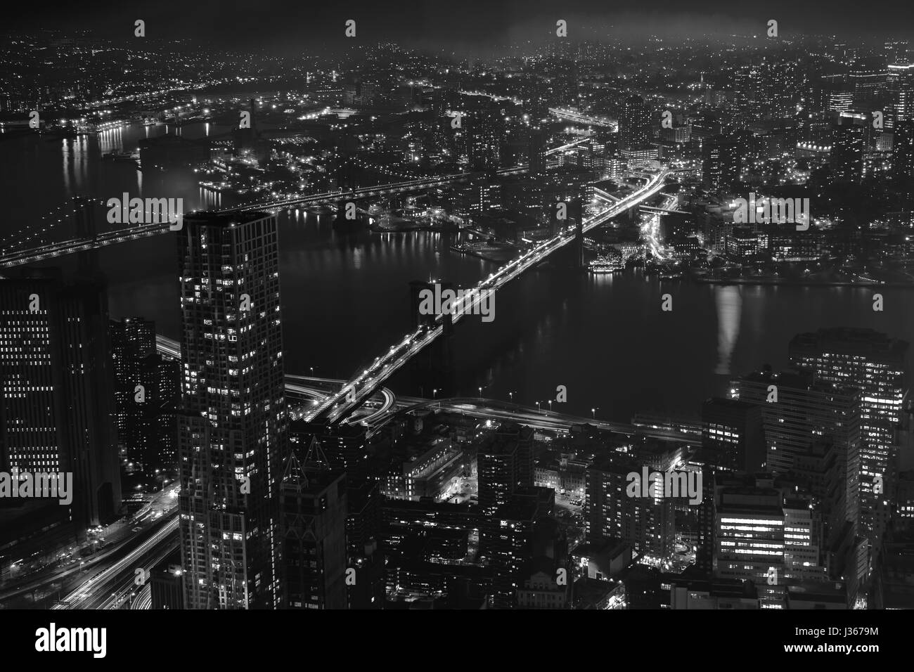 Edifici, grattacieli, strade, il Brooklyn e ponti di Manhattan di notte nella città di New York. Vista aerea. In bianco e nero Foto Stock