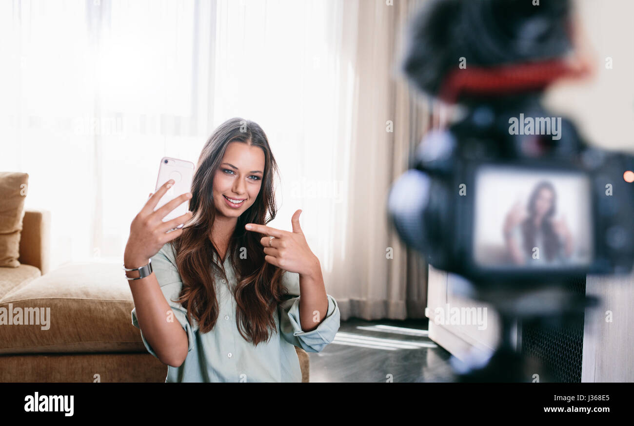 Azienda femmina smartphone, la registrazione di contenuti video per il suo blog. Giovani vlogger contenuto registrazione sulla fotocamera. Foto Stock