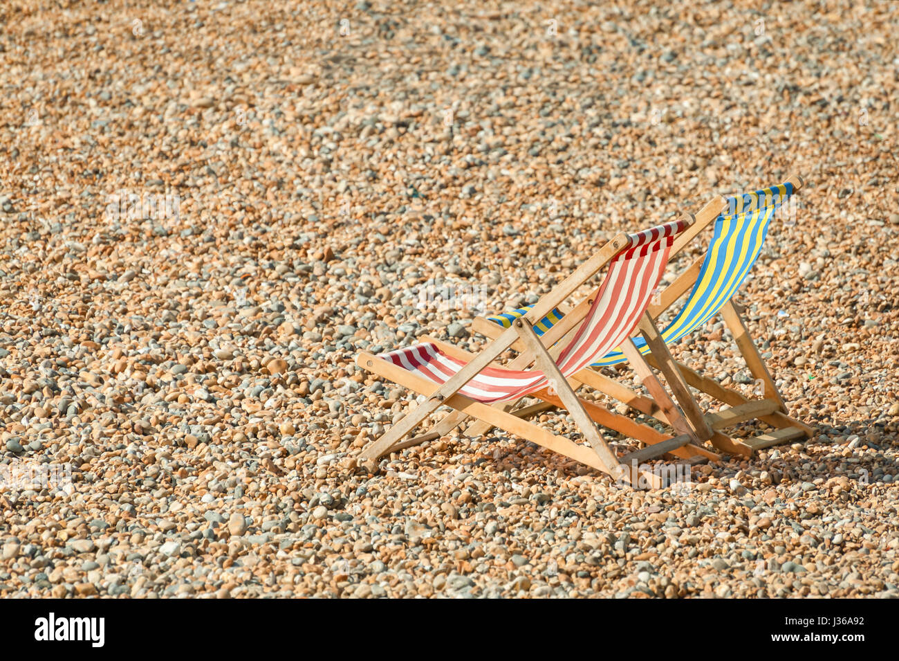 Due sedie a sdraio su una spiaggia di ciottoli in estate Foto Stock