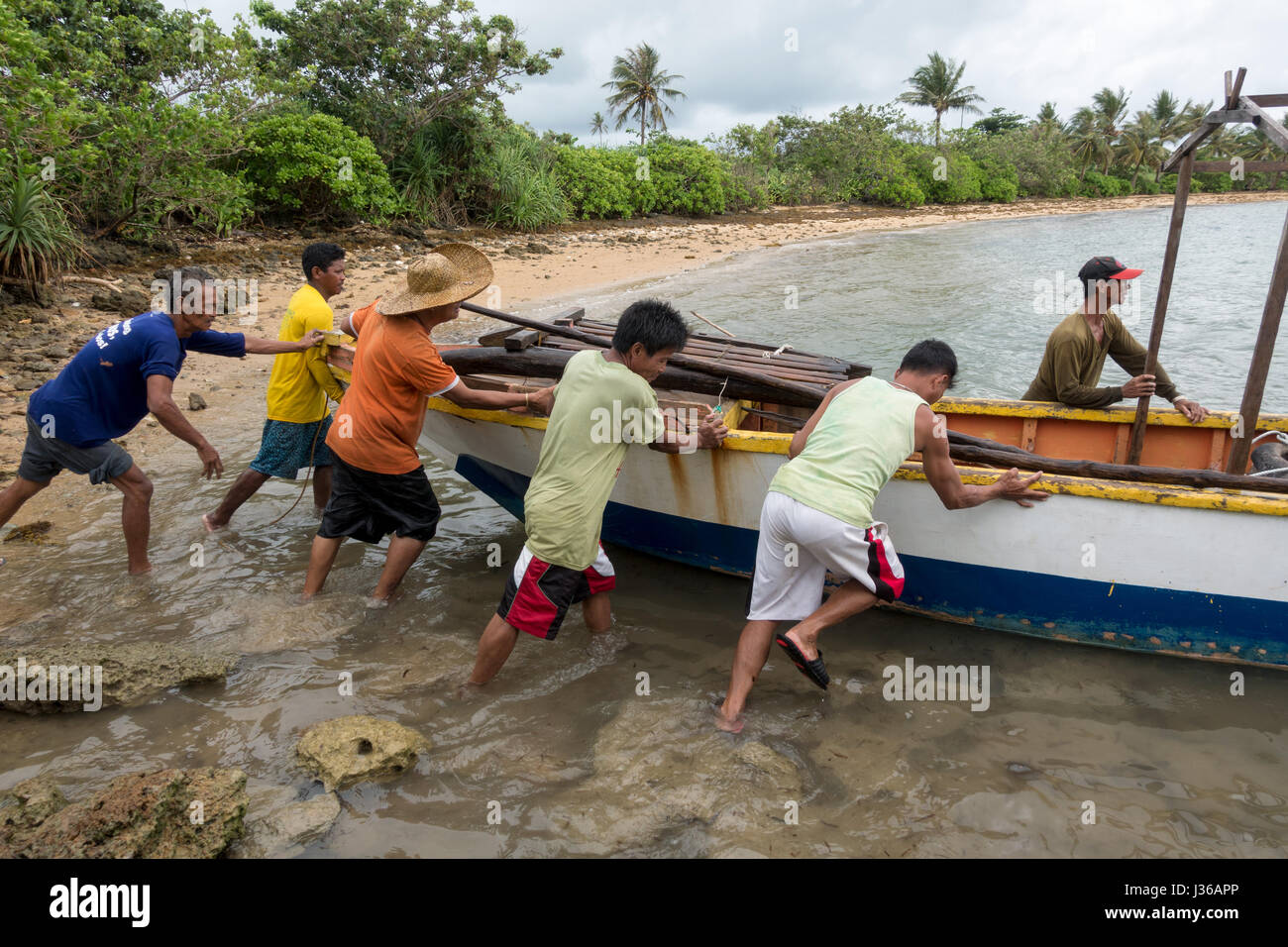 Isola Pandanan, Filippine - 30 Aprile 2017: gruppo di filippini pushin uomo una Banka barca al mare alla Pandanan isola nelle Filippine. Foto Stock