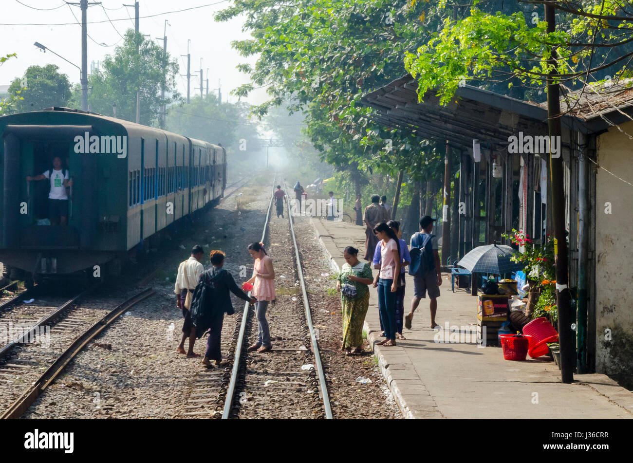 Le persone che attraversano le tracce ferroviarie vicino a un treno, Yangon, Myanmar, Foto Stock