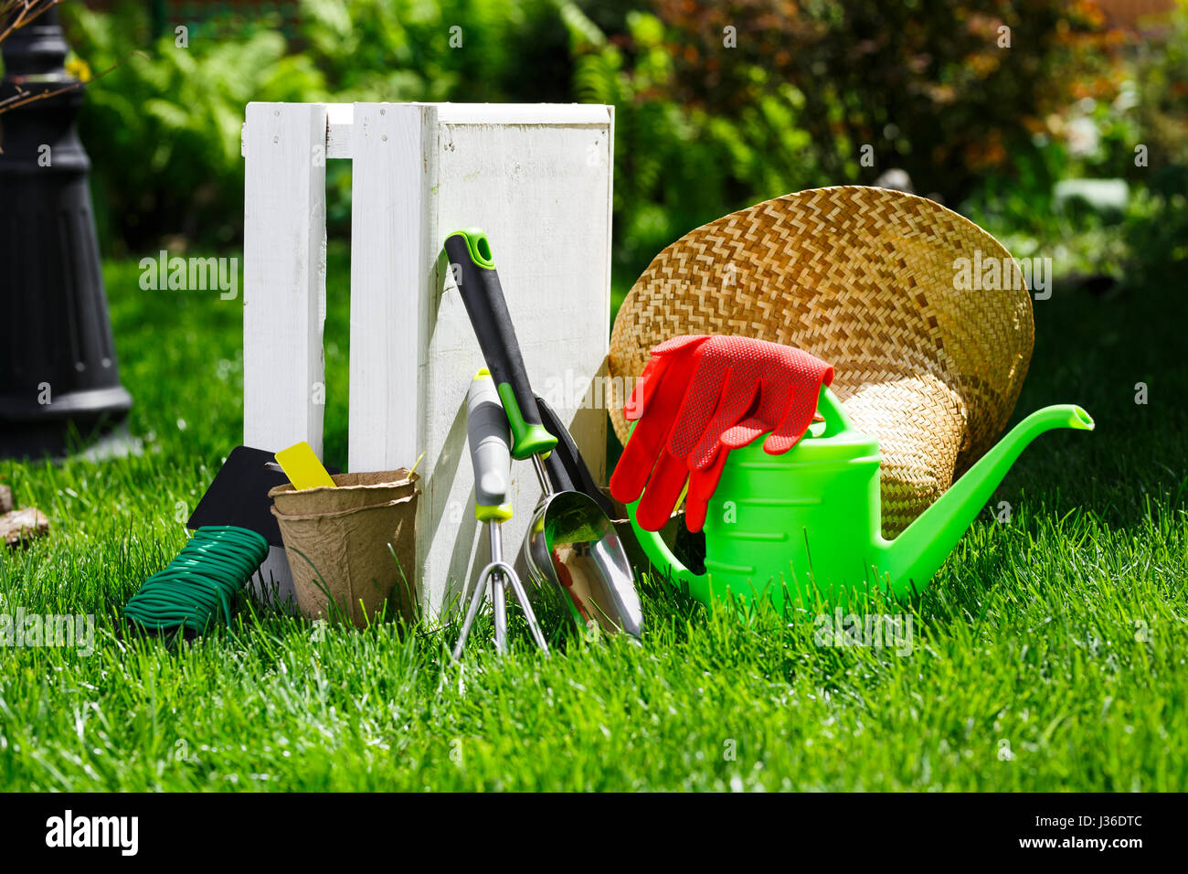 Utensili da giardinaggio e un cappello di paglia sull'erba nel giardino. Foto Stock