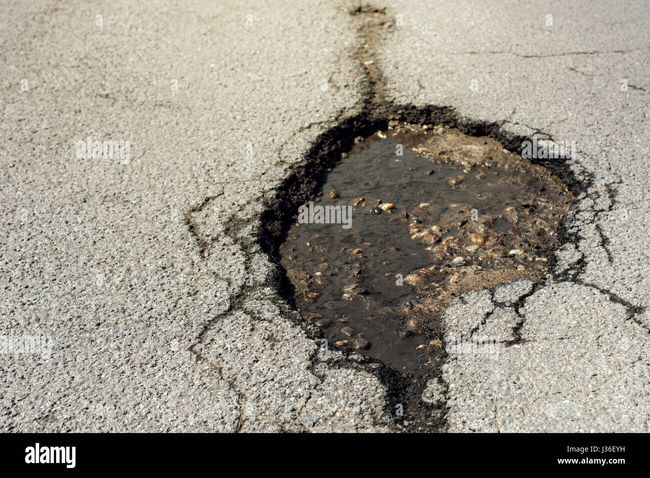 Strada asfaltata foro danni, in prossimità del viale di danneggiato Foto Stock