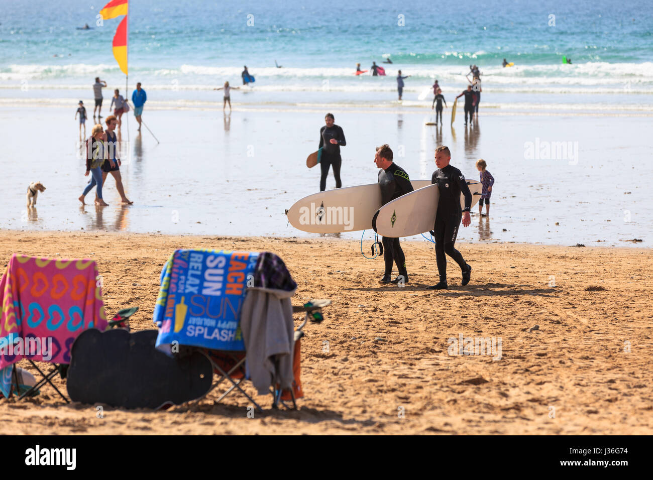 Newquay, Regno Unito. spiaggia frequentatori godetevi il sole in un ambiente luminoso e soleggiato nel pomeriggio a molla su Fistral Beach in Newquay. Surfers curiosi persone asciugamani Foto Stock