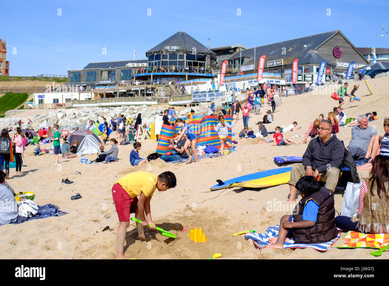 Newquay, Regno Unito. spiaggia frequentatori godetevi il sole in un ambiente luminoso e soleggiato nel pomeriggio a molla su Fistral Beach in Newquay. Foto Stock
