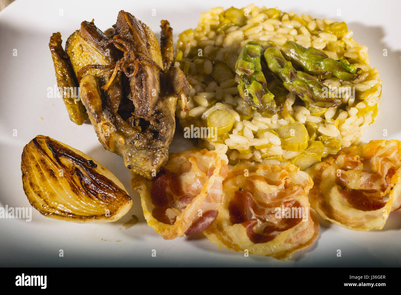 Piccione arrostito con asparagi verdi risotto e cipolla bianca e la pancetta da sopra particolare Foto Stock