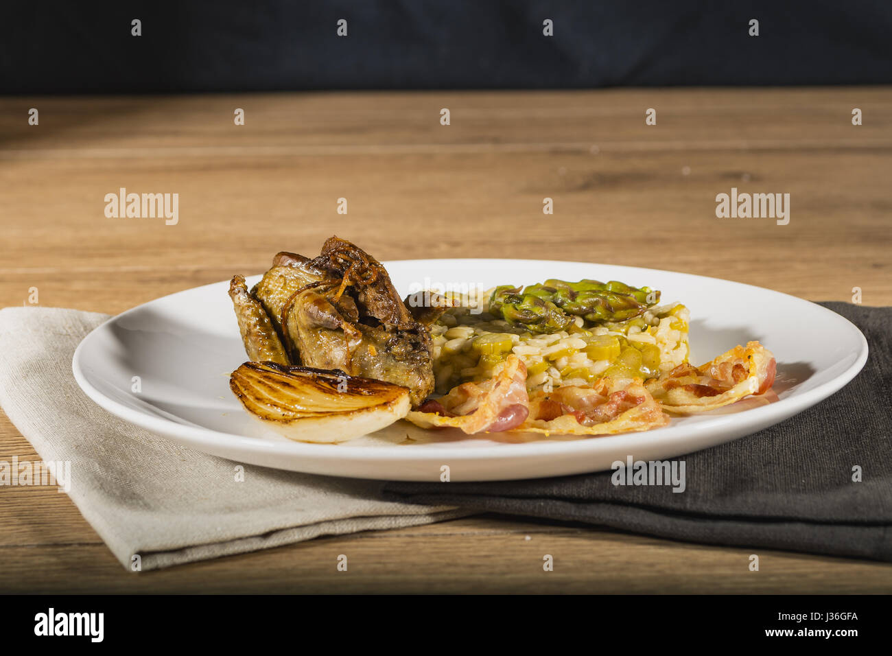 Piccione arrostito con asparagi verdi risotto e cipolla bianca e la pancetta da sotto Foto Stock