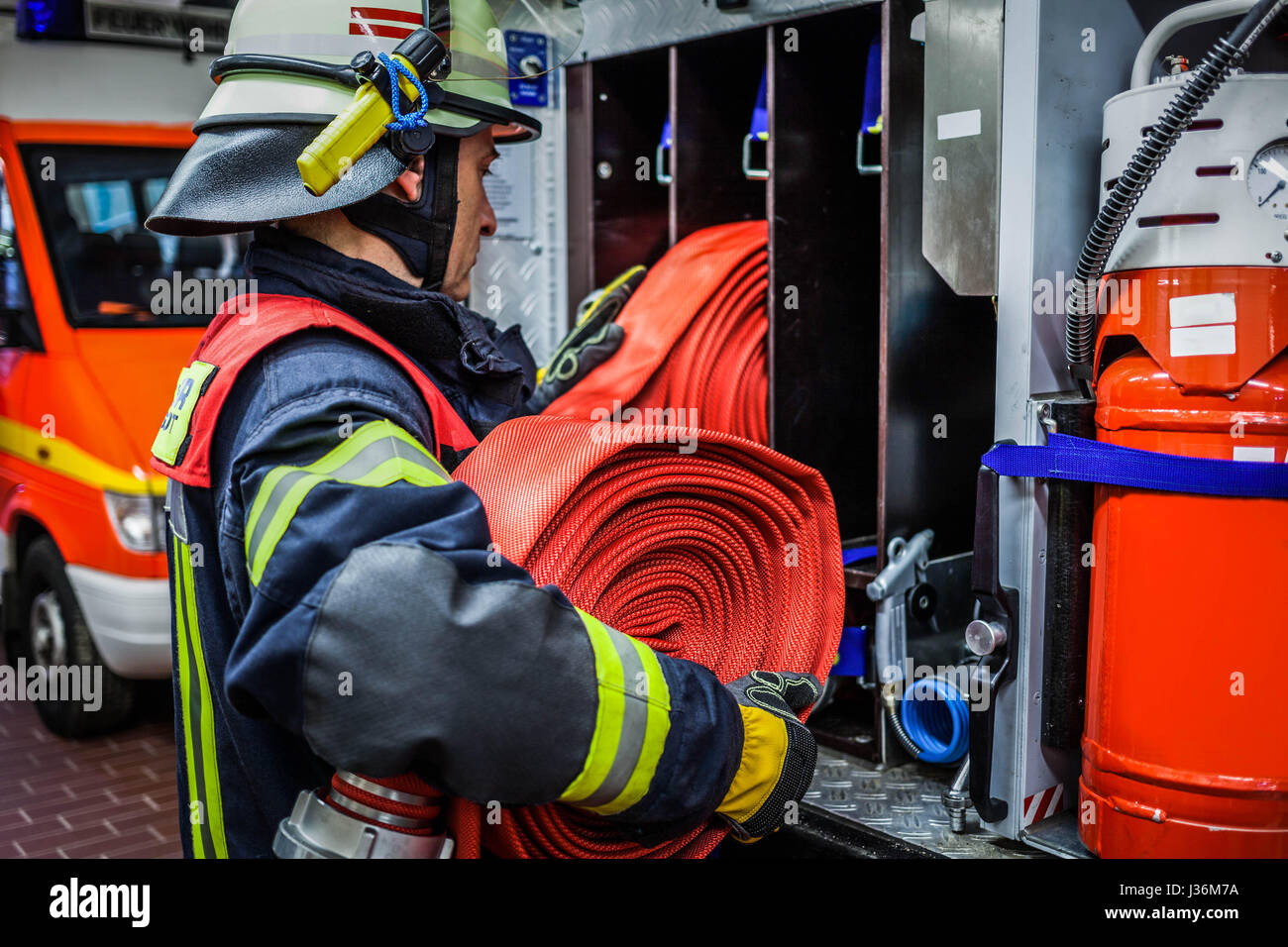 Vigile del fuoco nella stazione dei vigili del fuoco con un tubo flessibile di acqua in mano - HDR Foto Stock