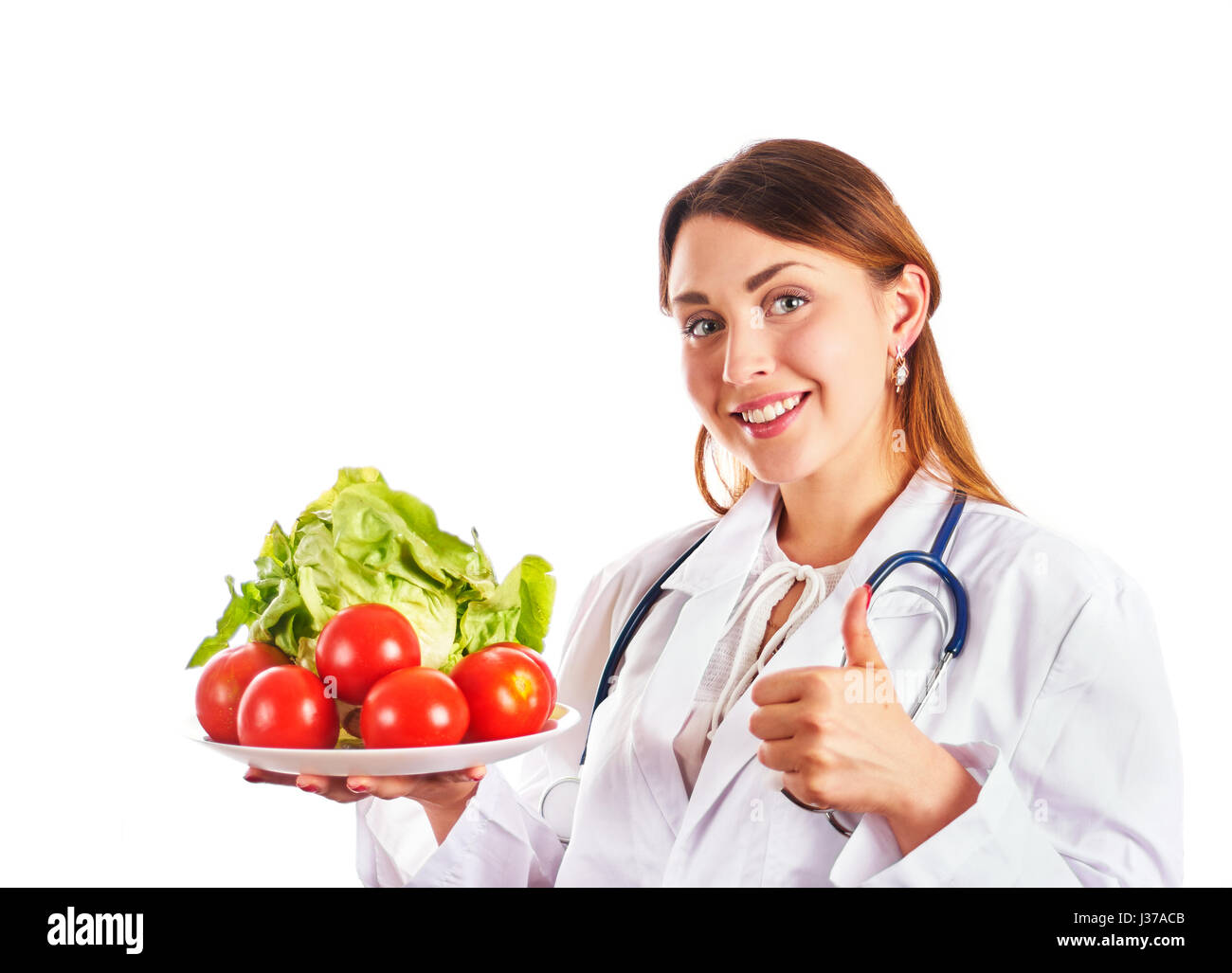 Donna in medic uniforme vaschetta di contenimento con verdure e gesticolando pollice in alto. Isolato su bianco. Copia dello spazio. Foto Stock
