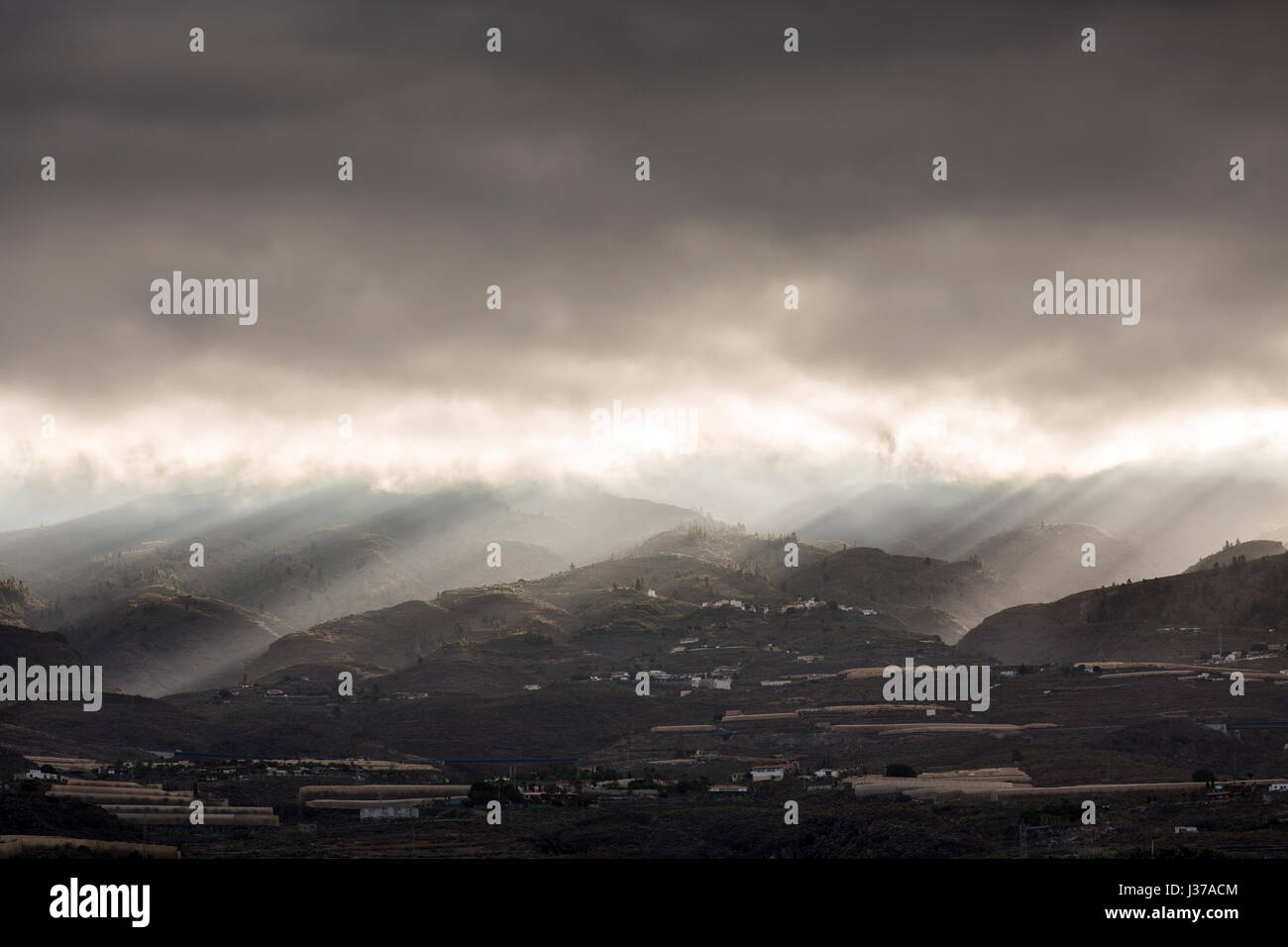 Raggi di sole risplendere nuvole temporalesche all'alba sopra le colline e le montagne a Guia de Isora sulla zona ovest di Tenerife, Isole Canarie, Spagna Foto Stock