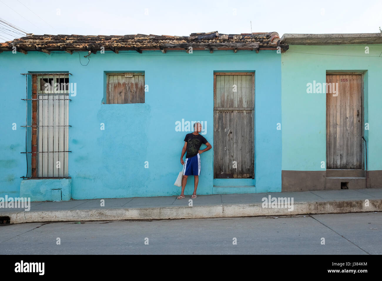 Scena di strada in Trinidad, Sancti Spiritus, Cuba. Locale uomo cubano in piedi di fronte a un color pastello edificio. Foto Stock