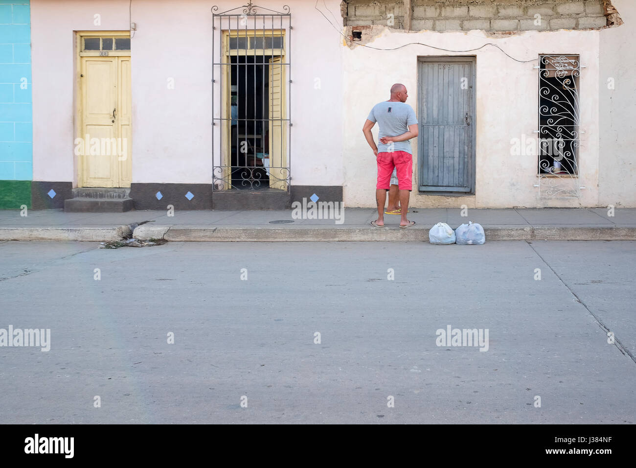 Scena di strada in Trinidad, Sancti Spiritus, Cuba. Locale uomo cubano in piedi di fronte a casa sua. Foto Stock