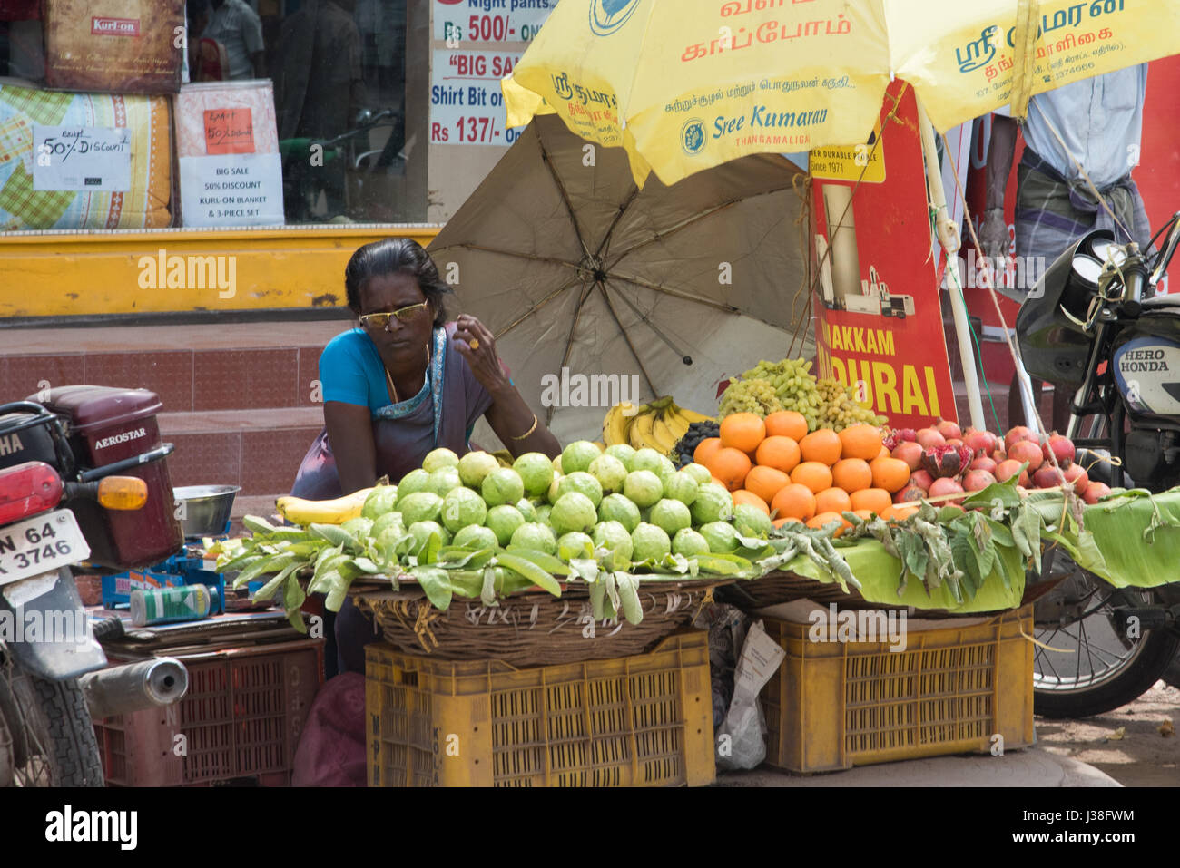 La donna per la vendita di frutta su un angolo di strada a Madurai, India Foto Stock