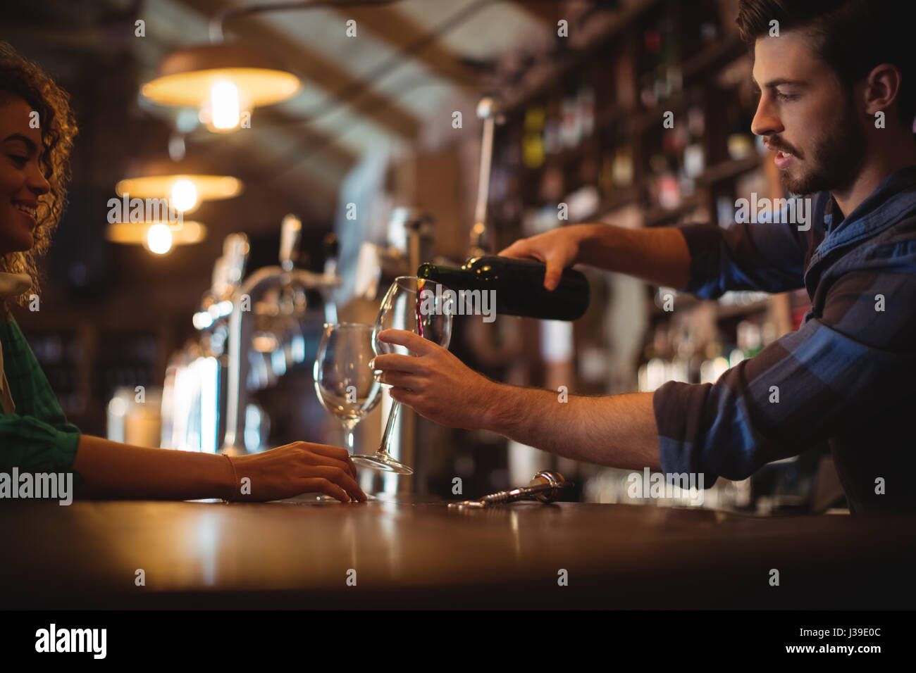 Barra maschio gara versando il vino in bicchieri al bancone bar Foto Stock