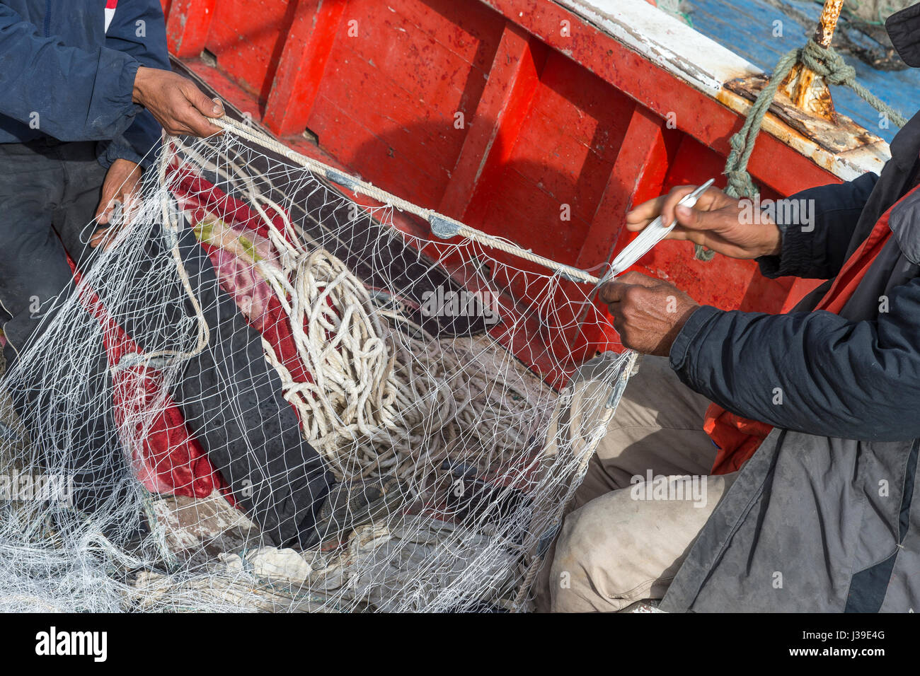 I pescatori sono visibili le riparazioni di reti da pesca sulla spiaggia di Houmt Souk Tunisia Foto Stock