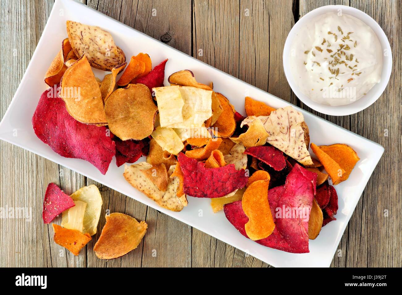 Piastra del colorato vegetale organico con chip dip vista verso il basso sul legno rustico Foto Stock