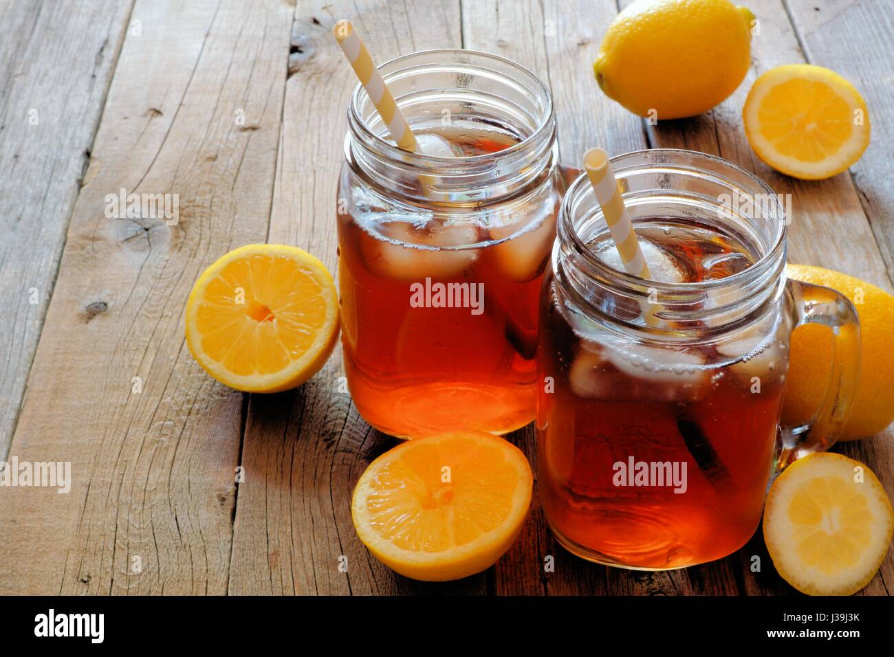 Due mason jar di occhiali in casa limone Tè freddo su un rustico sfondo di legno Foto Stock