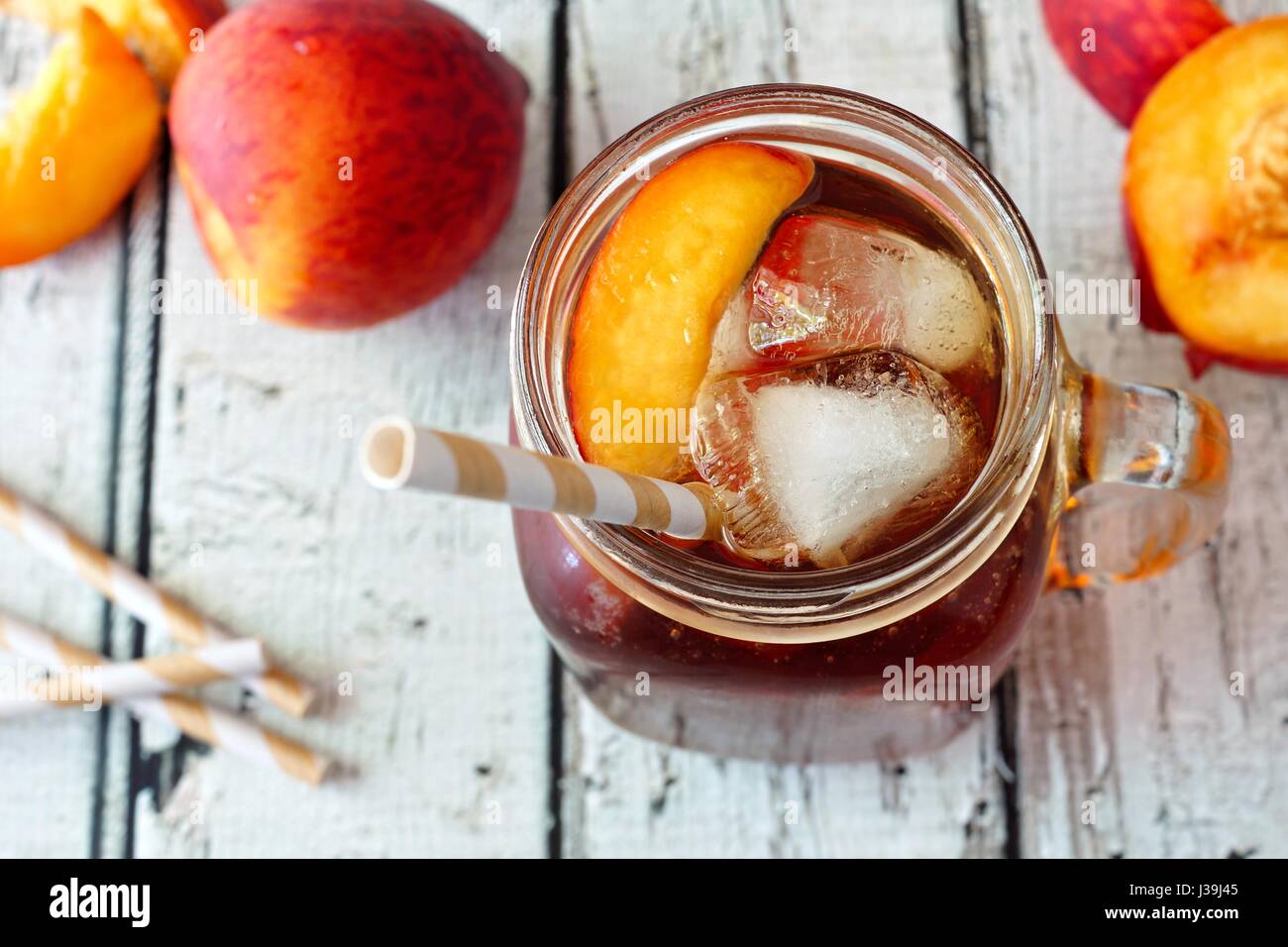 Mason vasetto di vetro in casa peach tè freddo su un rustico di legno bianco, sfondo vista verso il basso Foto Stock
