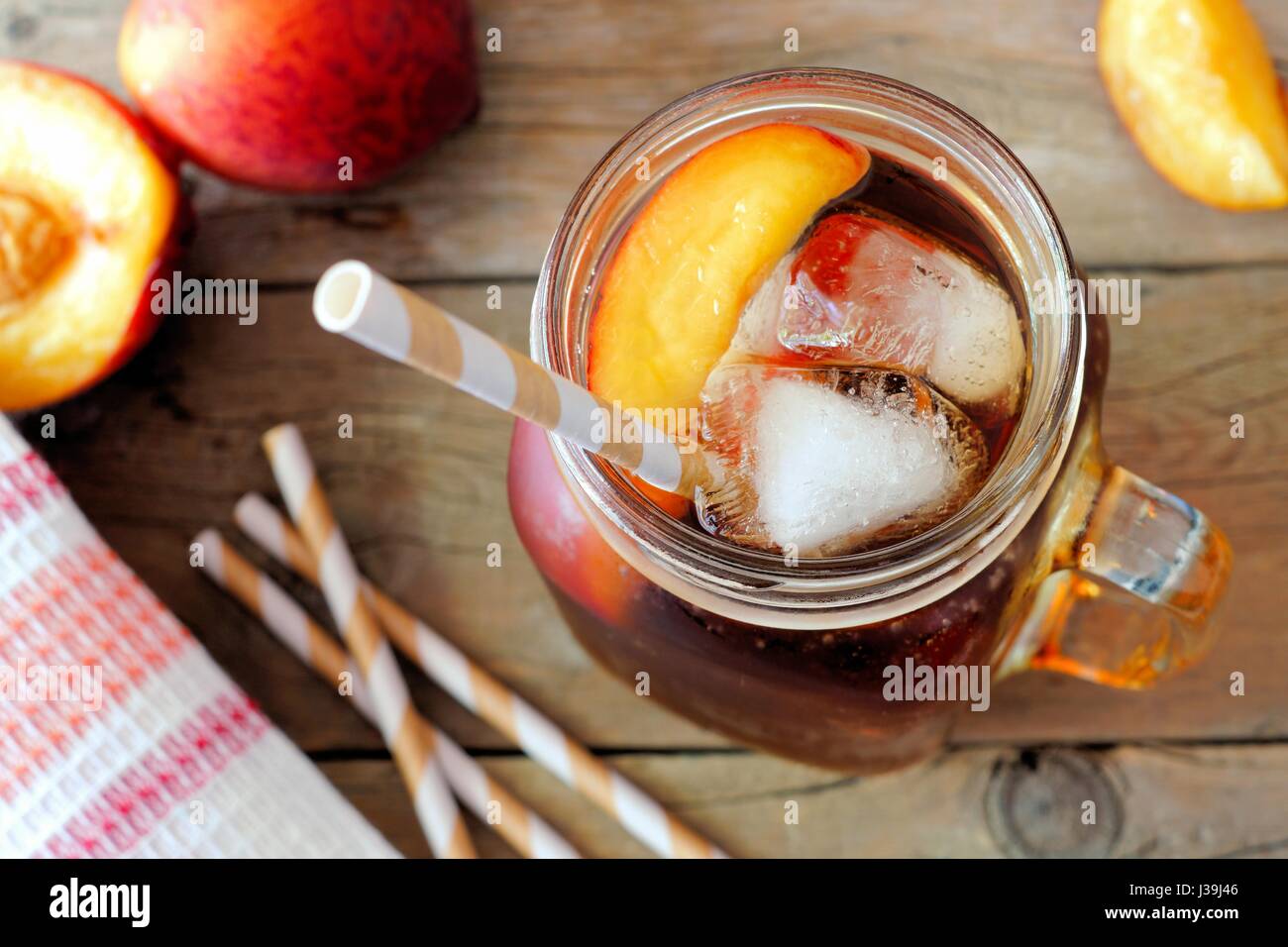 Mason vasetto di vetro in casa peach tè freddo su un legno rustico sfondo, vista verso il basso Foto Stock