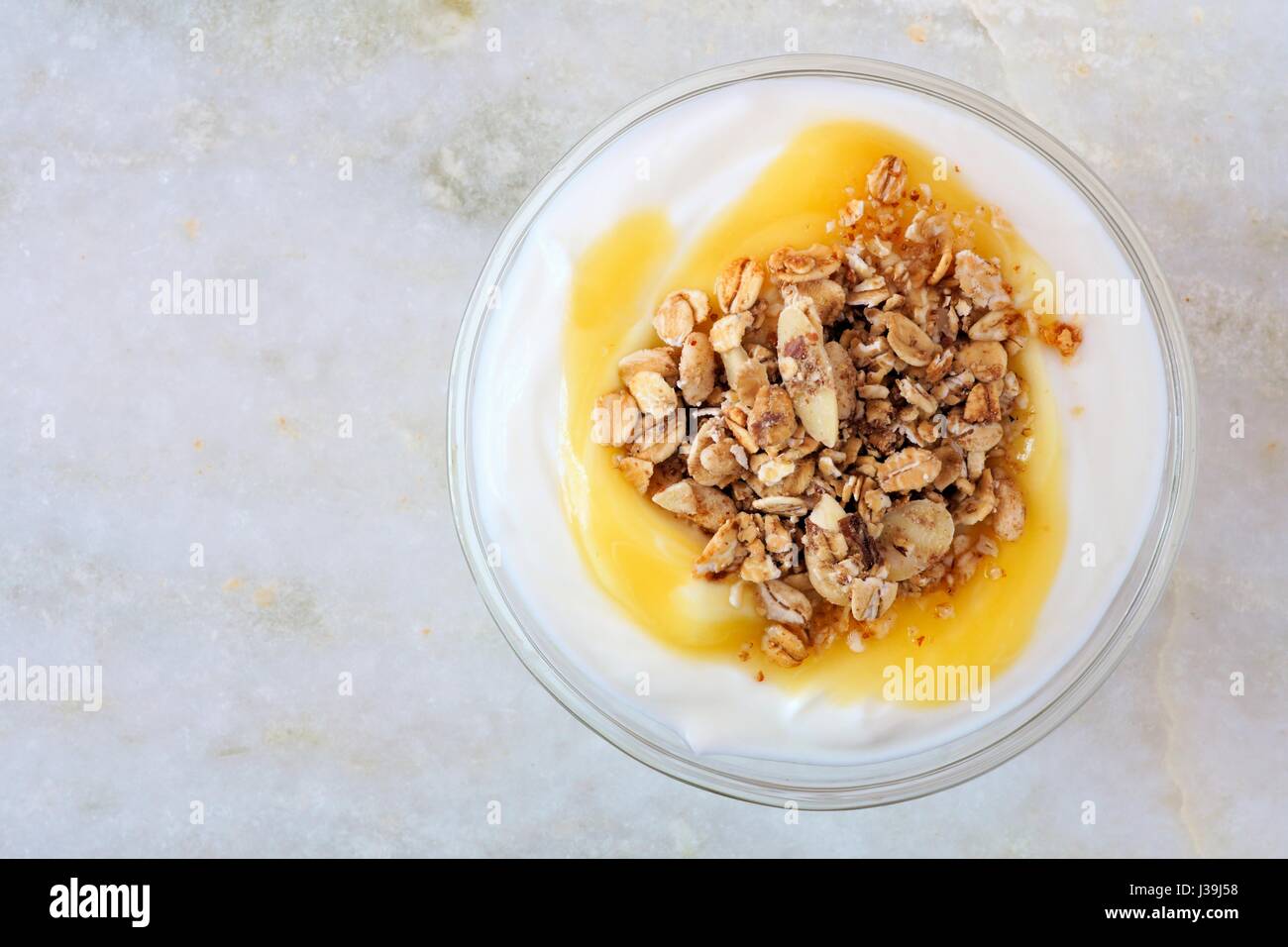 Aromatizzato al limone yogurt con muesli, vista aerea su marmo bianco sullo sfondo Foto Stock