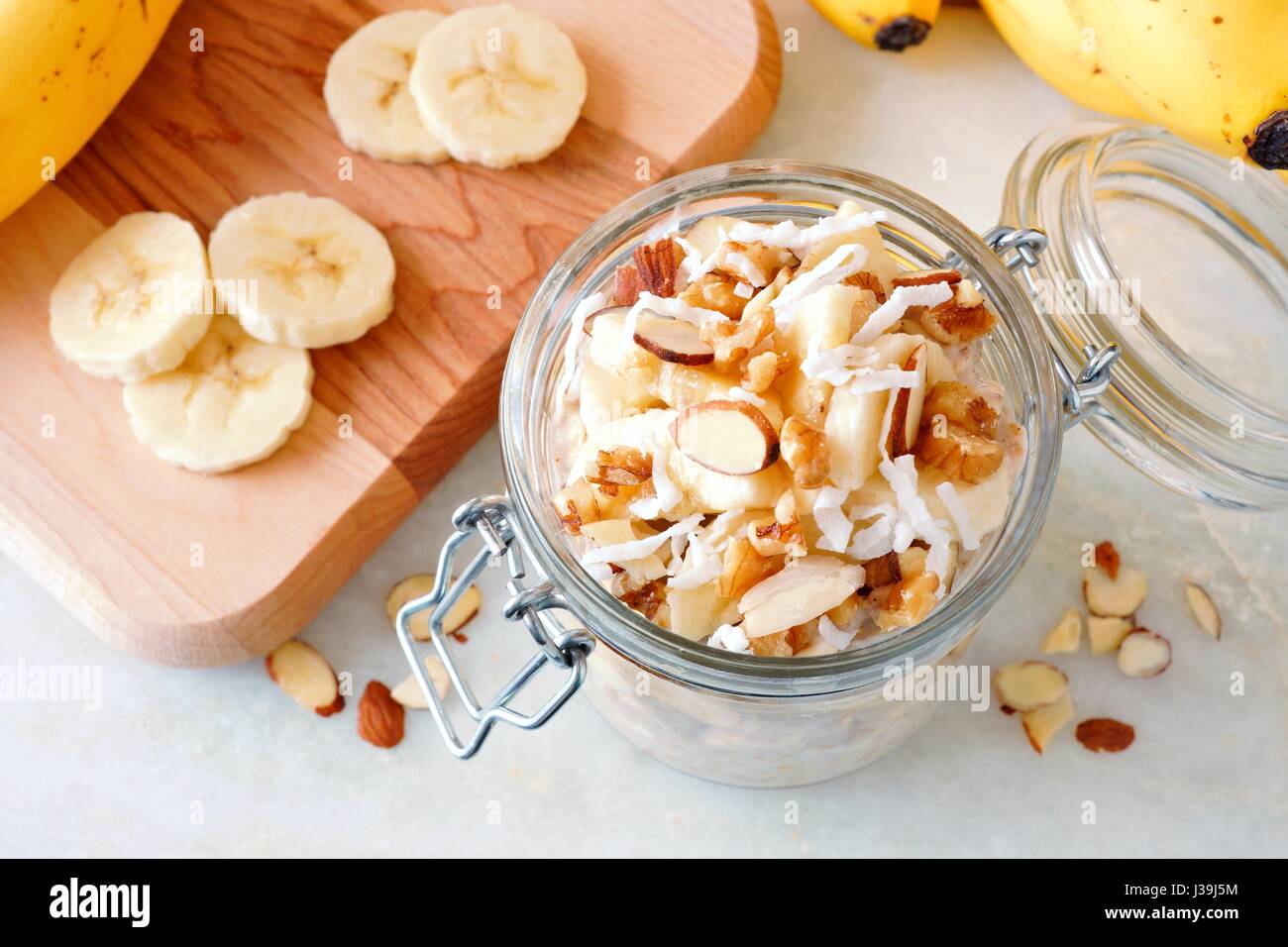 Dado di banane per tutta la notte di avena con in vetro canning jar su marmo bianco, vista verso il basso Foto Stock