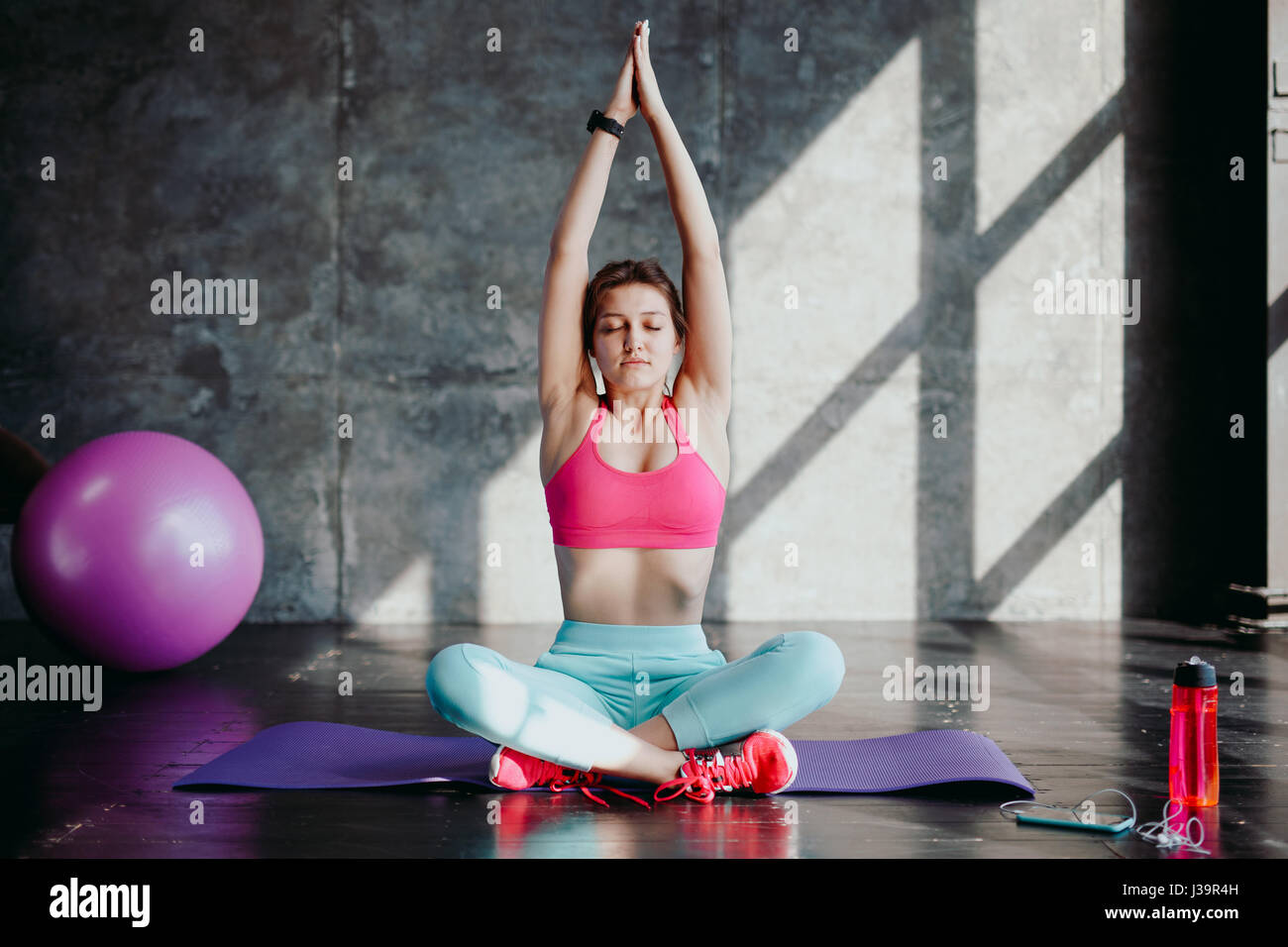 La donna a praticare yoga in lotus pongono indoor. Montare la ragazza di sportswear seduto in Padmasana esercizio, sessione di meditazione del mattino al fitness studio, Foto Stock