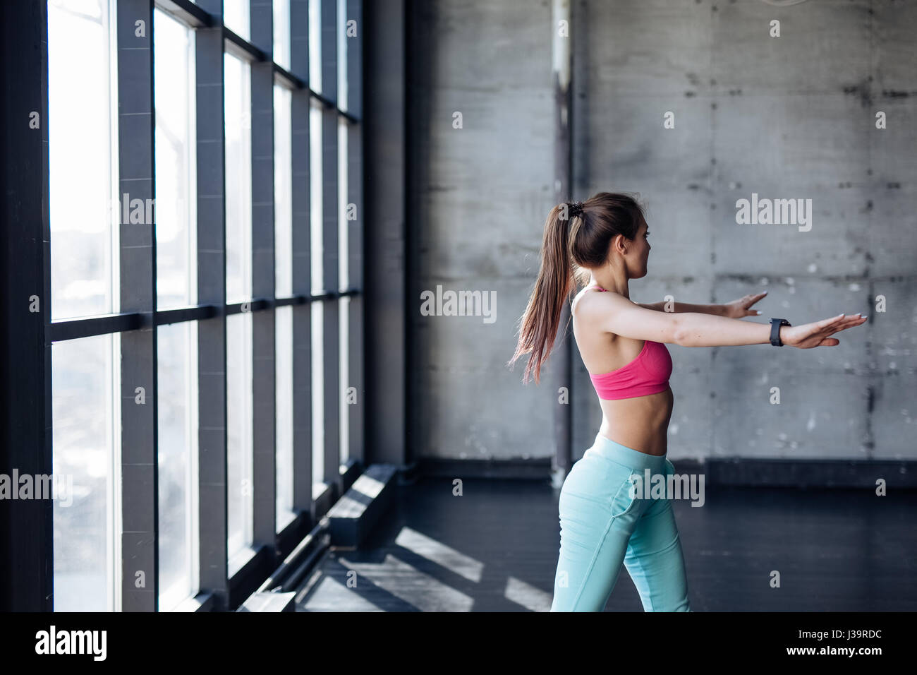 La ragazza di sportswear facendo esercizi del mattino sulla spiaggia e ascolto di brani musicali su cuffie, vista dal retro Foto Stock