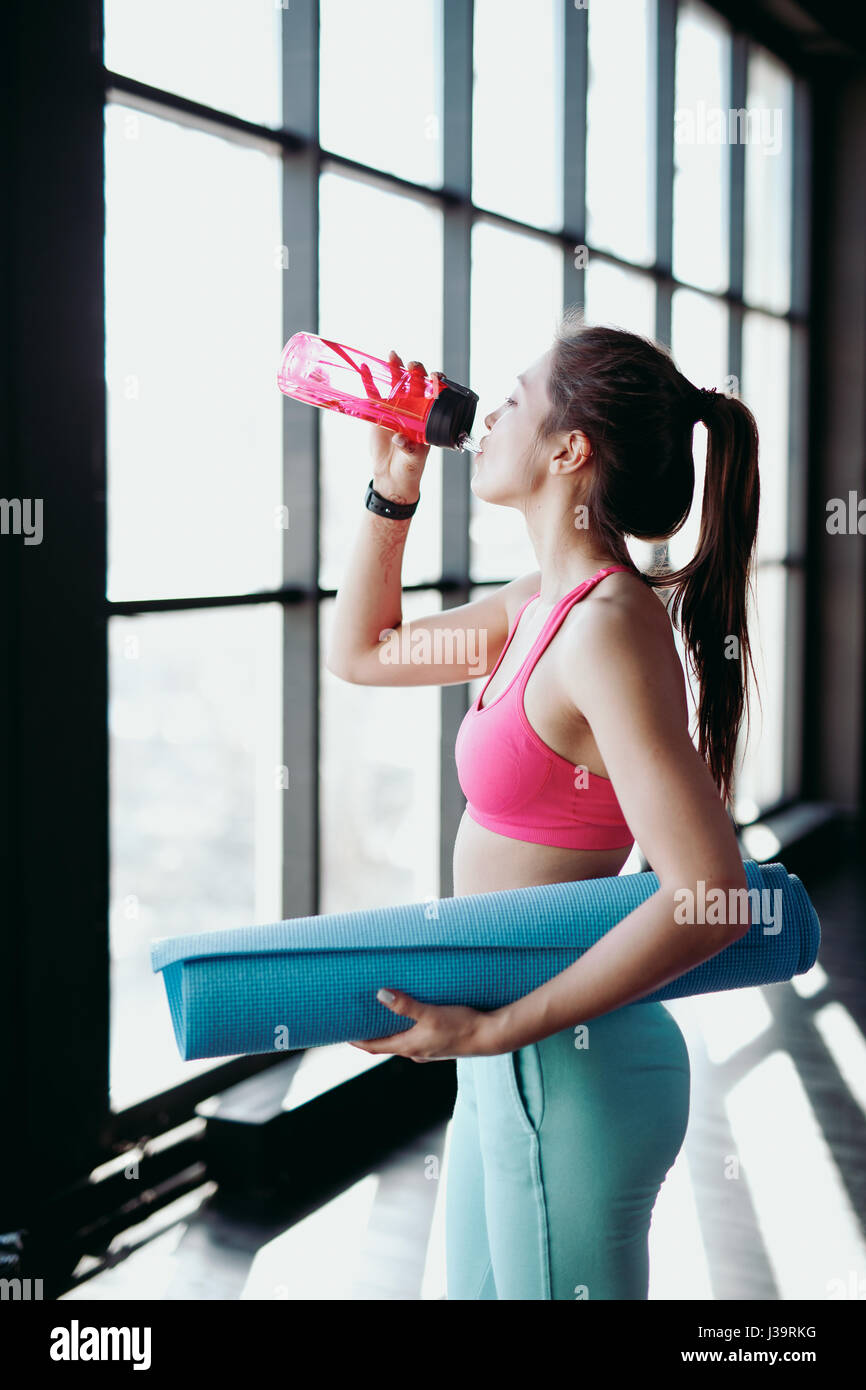 Atletica Giovane donna acqua potabile in palestra. Foto Stock